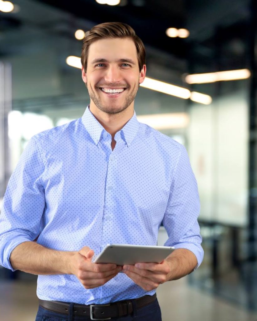 Homme souriant tenant une tablette dans un bureau moderne